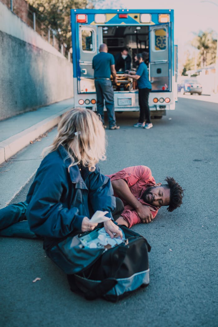 A paramedic aids a man injured on the roadside with ambulance support.